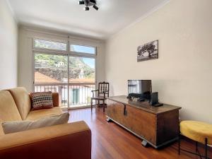 Una sala de estar con un sofá y un televisor. en Amarelo Apartment by Atlantic Holiday, en São Vicente