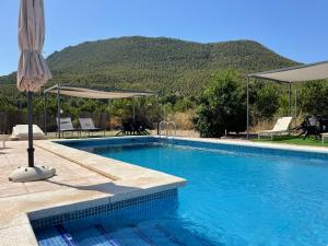 a swimming pool with an umbrella and chairs at Casas Amarillas. Finca el Campillo in Blanca