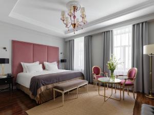 a bedroom with a large bed and a chandelier at Helvetia Hotel in Saint Petersburg