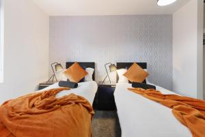 Home Away From Home - Contractors & Leisure في شيفيلد: غرفة نوم بسريرين وملاءات برتقالية