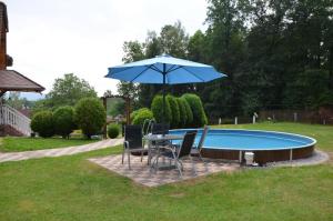 a table and chairs with an umbrella next to a pool at APARTMÁN POHODA in Svatava