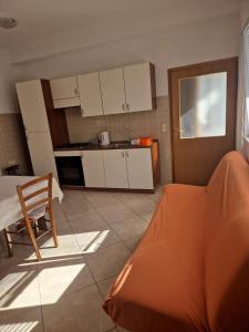 a kitchen with white cabinets and a couch in a room at Apartmani Biskup in Dugi Rat