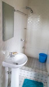 a white bathroom with a sink and a mirror at Sign of Silence Hostel in Kumasi