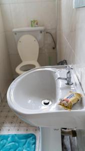 a bathroom with a white sink and a toilet at Sign of Silence Hostel in Kumasi