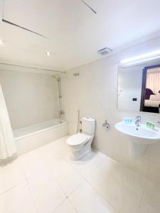 a bathroom with a toilet and a sink and a tub at Royal Garden Hotel in Beirut