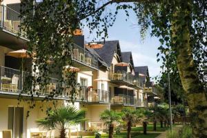 a large white building with balconies and palm trees at le loft de la riviéra in Bénodet
