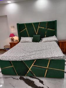 a bedroom with a large bed with a green headboard at Gupta Residence. in Dhanbād