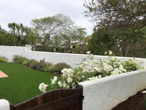 a garden with white flowers in a fence at Kate Stanton Inn in Encinitas