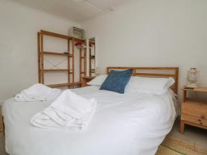 a bedroom with a white bed with towels on it at Blue Reef Cottage in Lower Boscaswell