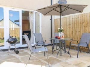 patio ze stołem, krzesłami i parasolem w obiekcie Pebble Bay w mieście Bideford