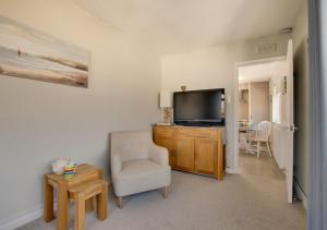 a living room with a television and a chair and a table at The Retreat 1 Alexandra Court in Swanage