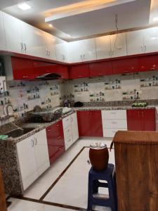 una cocina con armarios rojos y blancos y una olla en un taburete en Gupta Residence. en Dhanbād