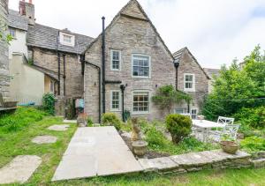 uma antiga casa de pedra com um jardim em frente em Wyvern Cottage em Swanage