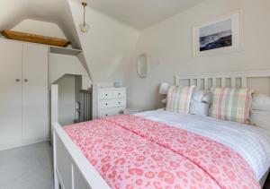 a bedroom with a pink bed and a dresser at Wyvern Cottage in Swanage