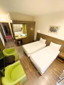 ベイルートにあるRoyal Garden Hotelのベッド2台と緑の椅子が備わるホテルルームです。