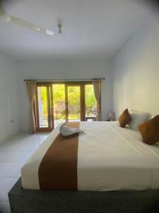 a bedroom with a large bed with a large window at Murni house in Ambat