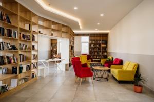 a library with yellow and red chairs and bookshelves at CIOM Apartment in Matuzići