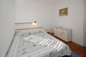 een slaapkamer met een bed met een blauwe en witte deken bij Apartman Nada in Punat