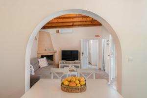 Mikros Paradeisos في ثيولوغيس: غرفة معيشة مع طاولة مع وعاء من البرتقال