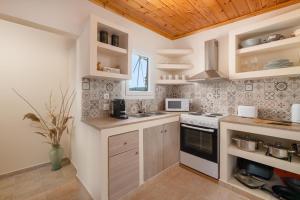 a kitchen with white walls and wooden ceilings at Mikros Paradeisos in Theologos