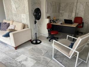 ein Wohnzimmer mit einem weißen Sofa und einem Schreibtisch mit einem Computer in der Unterkunft Studio Universitário in Jacobina
