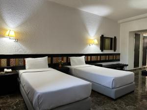 two beds in a hotel room with two bedsskirts at Ourida Urban Hotel Rabat in Rabat