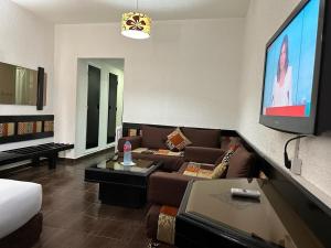 Ourida Urban Hotel Rabat في الرباط: غرفة معيشة مع أريكة وتلفزيون بشاشة مسطحة