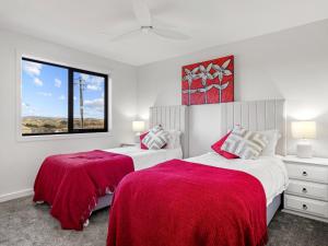 a white bedroom with two beds with red blankets at Luxury 5 Bedroom Home - Sentinel Chalet - Snowy Mountains - Jindabyne in Jindabyne