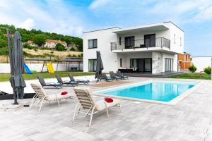 a villa with a swimming pool in front of a house at Luxury Villa Rilassante-Heated Pool,Full Privacy,Children Playground in Sinj