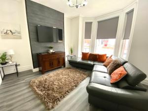 a living room with a leather couch and a flat screen tv at Warley House 4 Bed -Blackpool North -Family House in Blackpool
