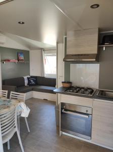 卡內的住宿－Mobil Home Camping Mar Estang 4*，厨房以及带炉灶和桌子的客厅。
