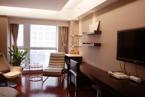 a living room with a flat screen tv and chairs at Kaibin Apartment- Nanjing University Branch in Nanjing