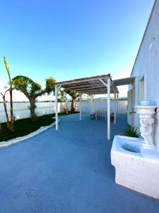 a patio with a white pergola next to the ocean at Villa Santo Stefano in Monopoli