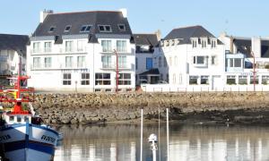 Plobannalec-LesconilにあるLogis Hotel Du Portの建物の前の水に船が停泊している