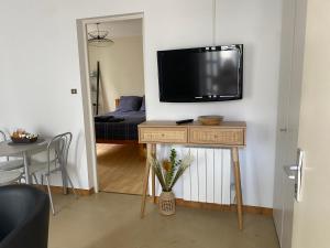 a living room with a television on a wall with a table at Confortable et agréable T1 n•1 in Ussel