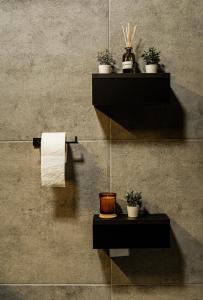 baño con toallas y plantas en la pared en Black Velvet Apartman en Sisak