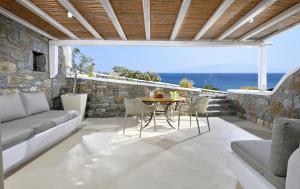 eine Terrasse mit einem Tisch, Stühlen und Meerblick in der Unterkunft VLIA Mykonos in Kalafatis