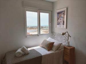Habitación blanca con cama y ventana en Mirando a dos mares, en La Manga del Mar Menor