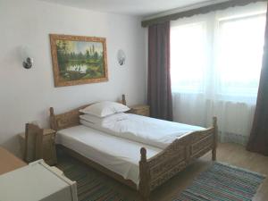 ein Schlafzimmer mit einem Bett mit einem Bild an der Wand in der Unterkunft Pensiunea Agroturistica Cristal in Suceviţa