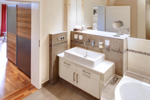 ein Badezimmer mit einem weißen Waschbecken und einem Spiegel in der Unterkunft Appartements Coloman in Schwangau