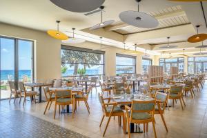 Creta Maris Resort في خيرسونيسوس: غرفة طعام مع طاولات وكراسي والمحيط