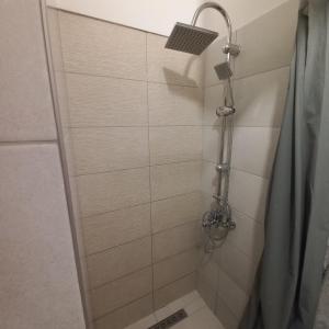 y baño con ducha con cabezal de ducha. en Belvárosi Apartman Vásárosnamény, en Vásárosnamény