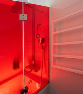 パリにあるHôtel Félicien & SPAの赤い壁のシャワー付きの赤いバスルーム
