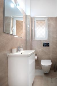 bagno con lavandino, servizi igienici e specchio di ILIADA Luxury Apartment a Porto Rafti
