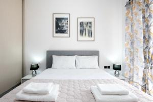 una camera da letto con un grande letto bianco con due cuscini di ILIADA Luxury Apartment a Porto Rafti