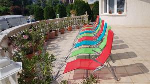 Pihenés Háza-Relax Apartmanhaus في جينيسدياس: صف من الكراسي الملونة يجلس على الفناء