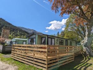 una caravana verde con una valla de madera alrededor en The Castleton 20, en Ardentinny