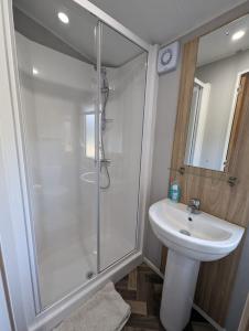 a white bathroom with a shower and a sink at The Castleton 20 in Ardentinny