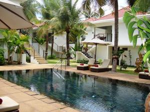 a swimming pool in front of a house with palm trees at Apsara Greenland Boutique Villa & Resort in Siem Reap
