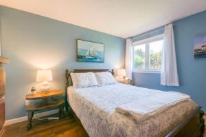 een blauwe slaapkamer met een bed en een raam bij 5 Bryant Road Bourne Sunset Cottage in Buzzards Bay